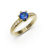 Gold ring with a blue gemstone and smaller diamonds on a white background